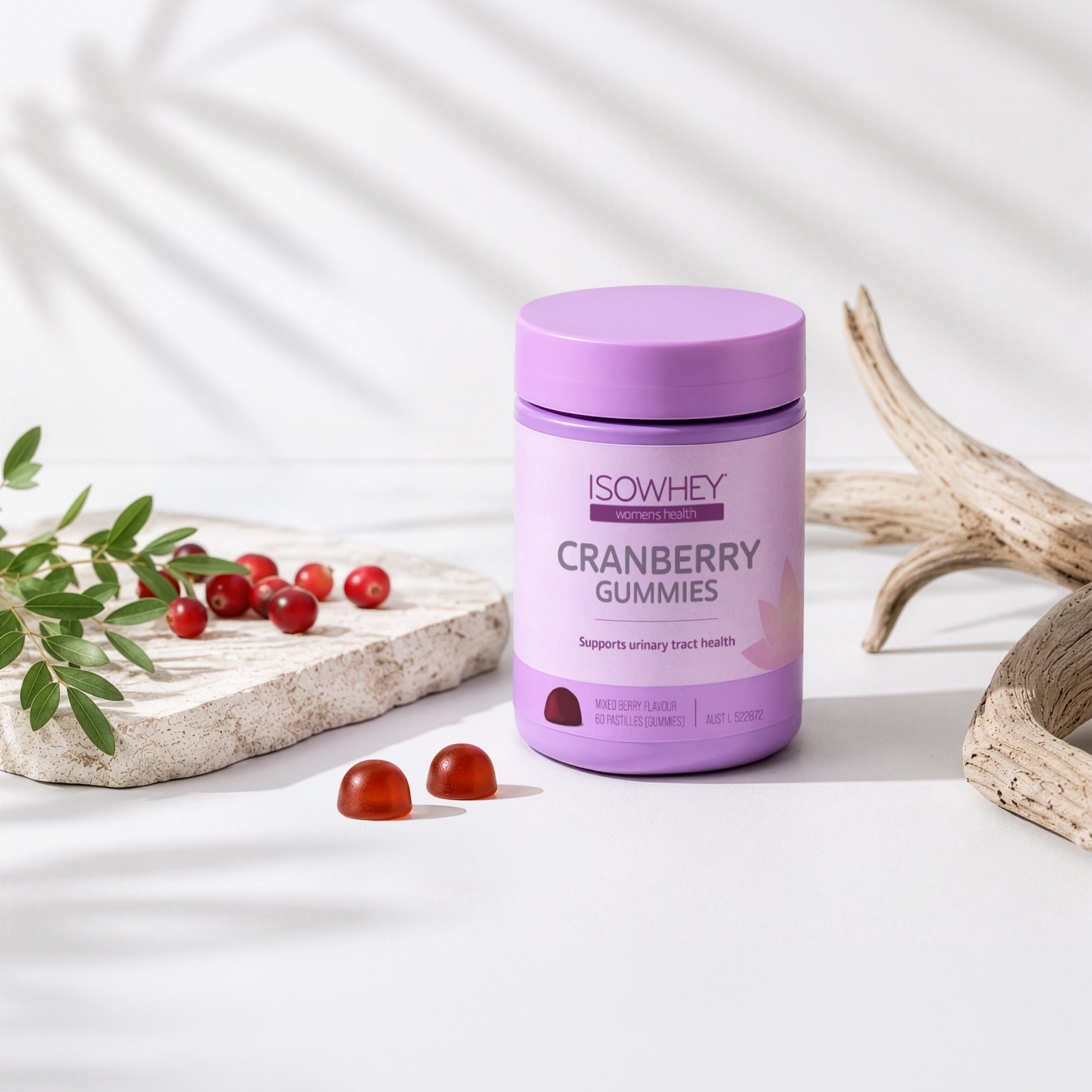 Purple container of ISOWHEY Cranberry Gummies on a light background with cranberries and leaves.
