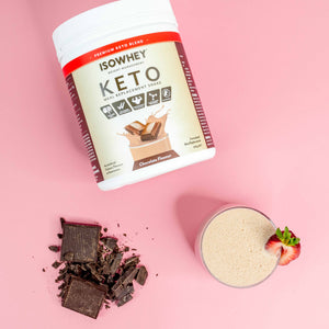 Headshot: IsoWhey Chocolate Keto Meal Replacement Shake 550g pack with ready-to-drink glass and chocolate pieces on a pink floor.