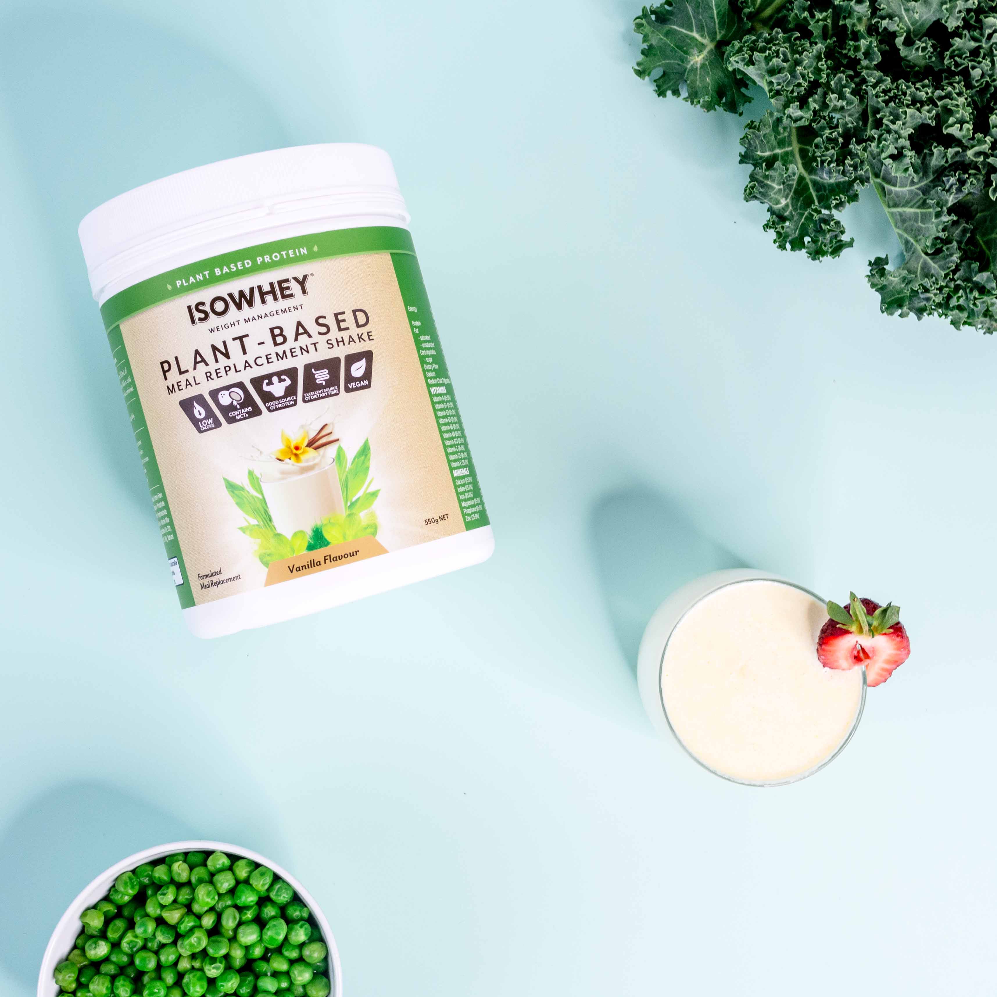 Overhead view: IsoWhey Vanilla Plant-Based Meal Replacement Shake 550g pack with ready-to-drink glass and green ingredients.